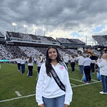 Marola Anes, fourth-year biology student, standing on the field at Penn State's Homecoming football game.