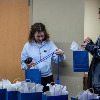Jennelle Malcos watches as a student open a bag with her commencement stole.