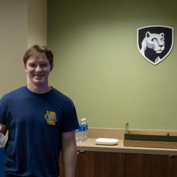 A student poses for a photo while holding his gift bag.