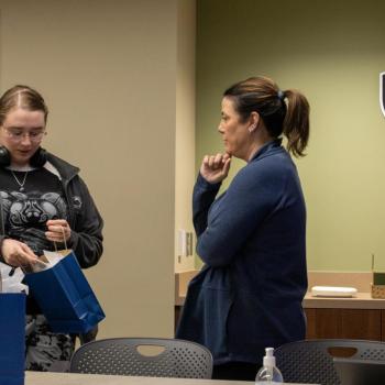 A coed opens her gift bag while a representative of our alumni relations office looks on.