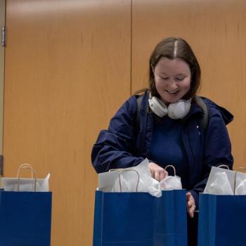A different coed stands in front of her gift bag with a look of anticipation.
