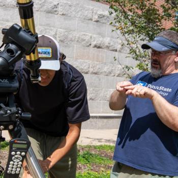 Chris Palma instructing someone how to use a telescope at the Science Involvement Fair.
